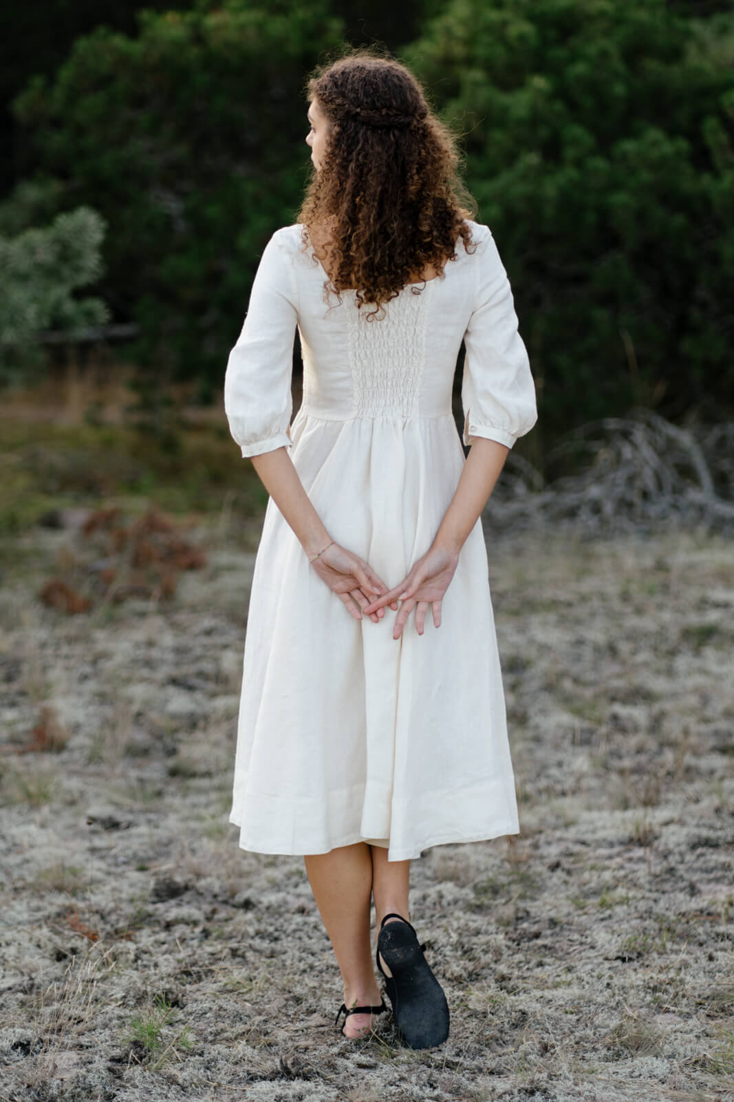 A lady in a hemp dress from Son de Flor standing backwards in the forest