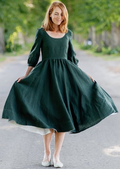 Smiling woman walking through the trees in a Son de Flor linen dress